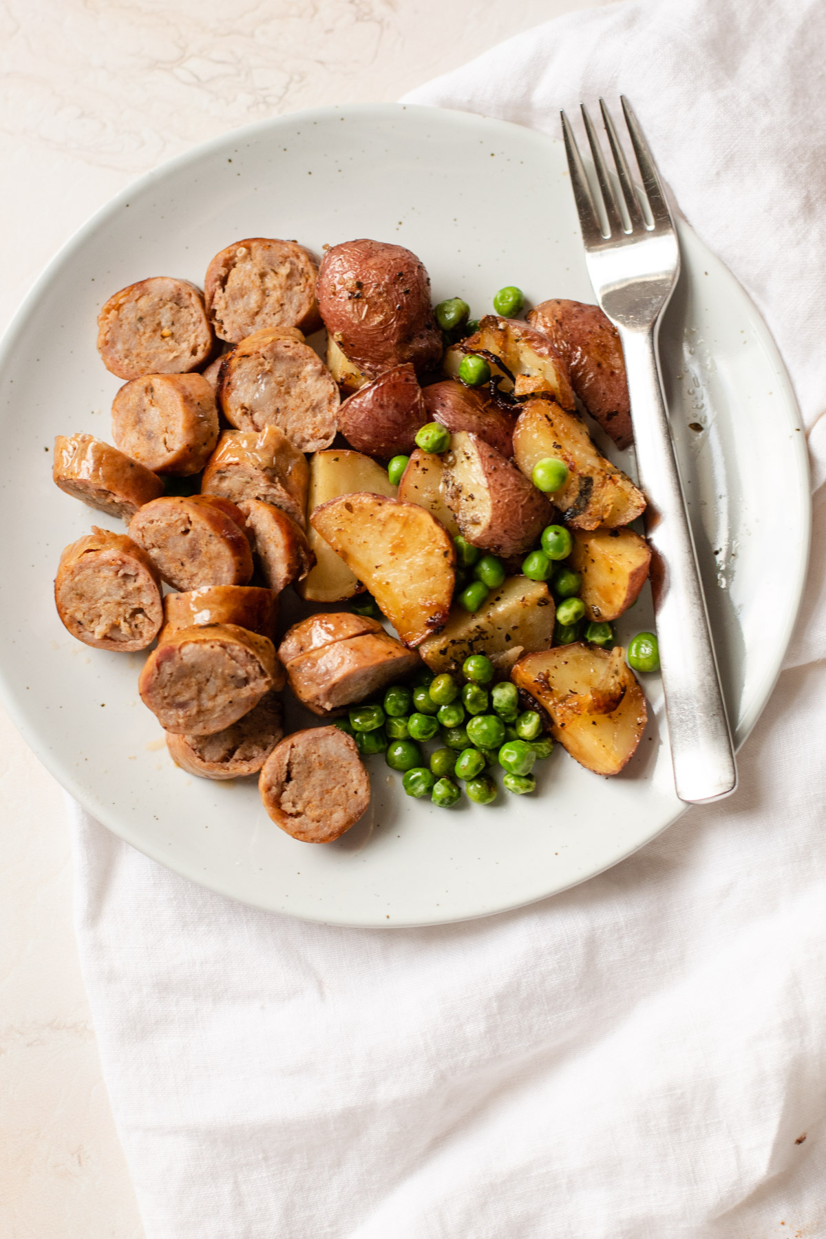 A plate of sausage potatoes and peas.