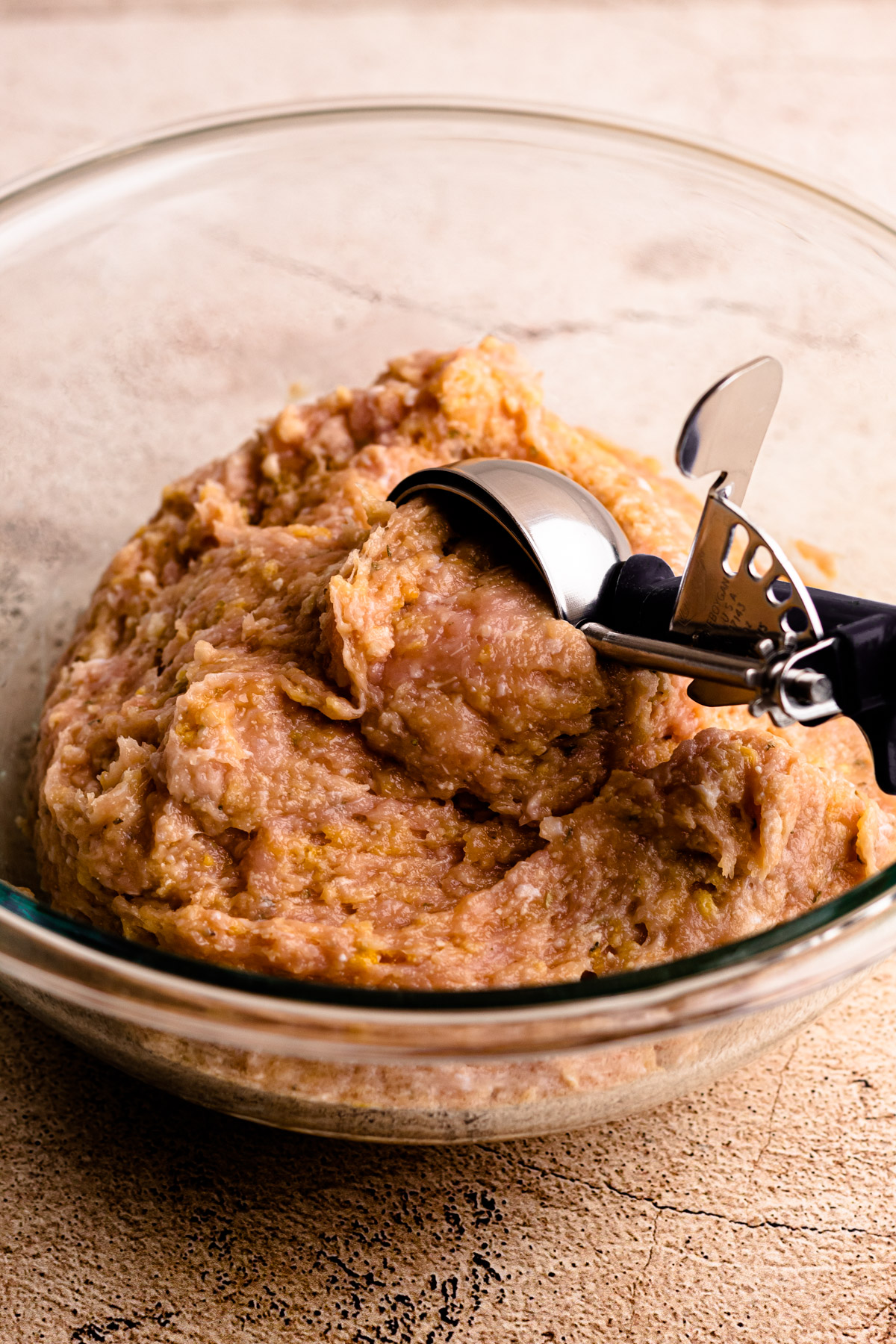 Chicken parm meatball mixture being scooped out.