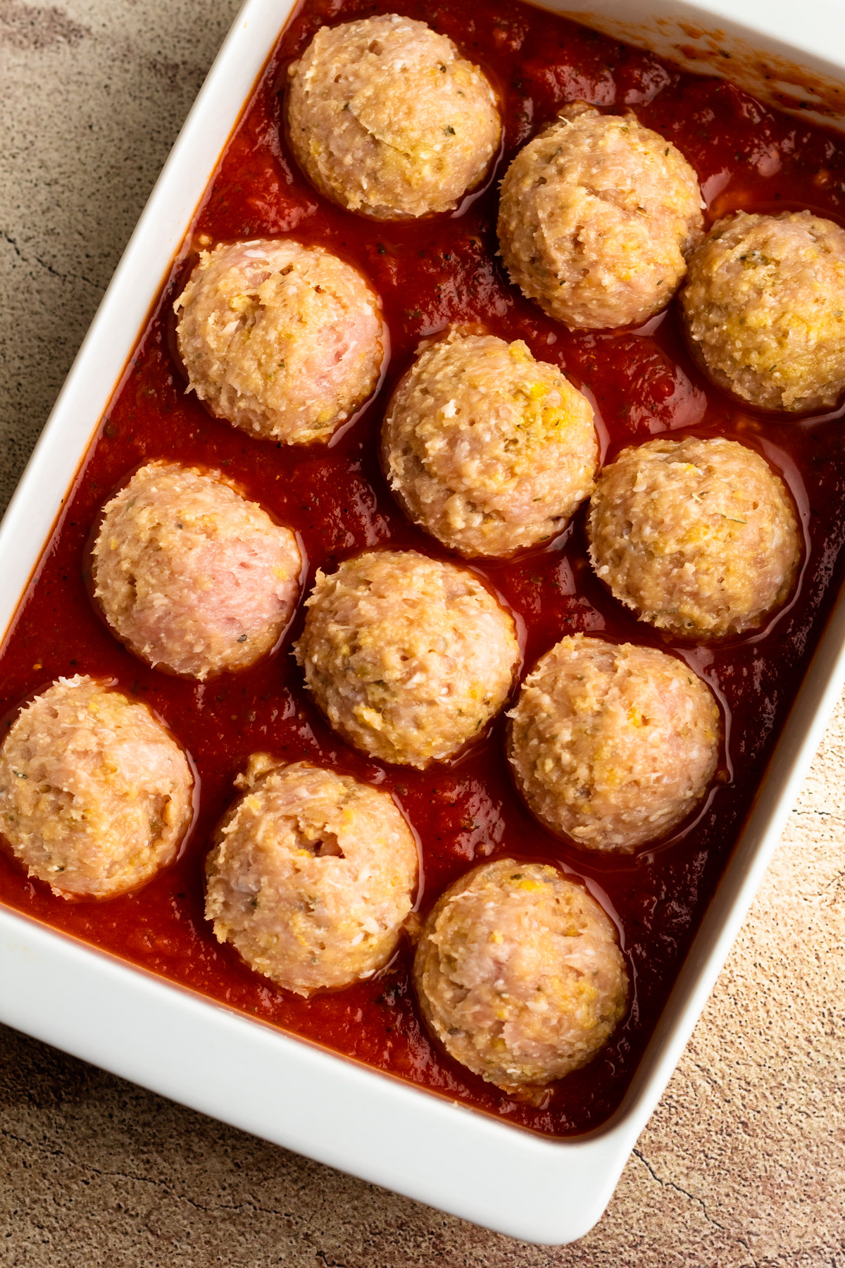 Chicken meatballs in a casserole dish with marinara.