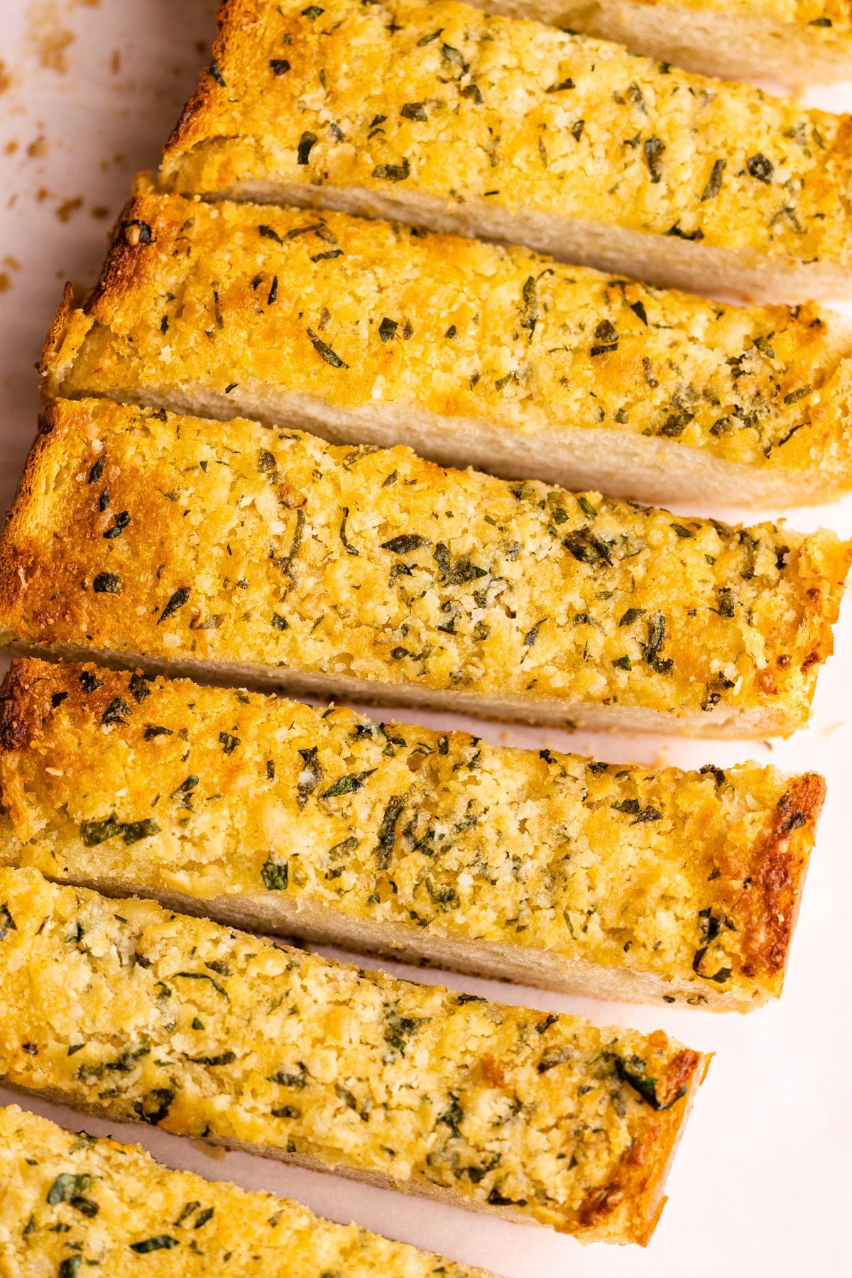 A loaf of garlic bread made from scratch sliced into pieces.