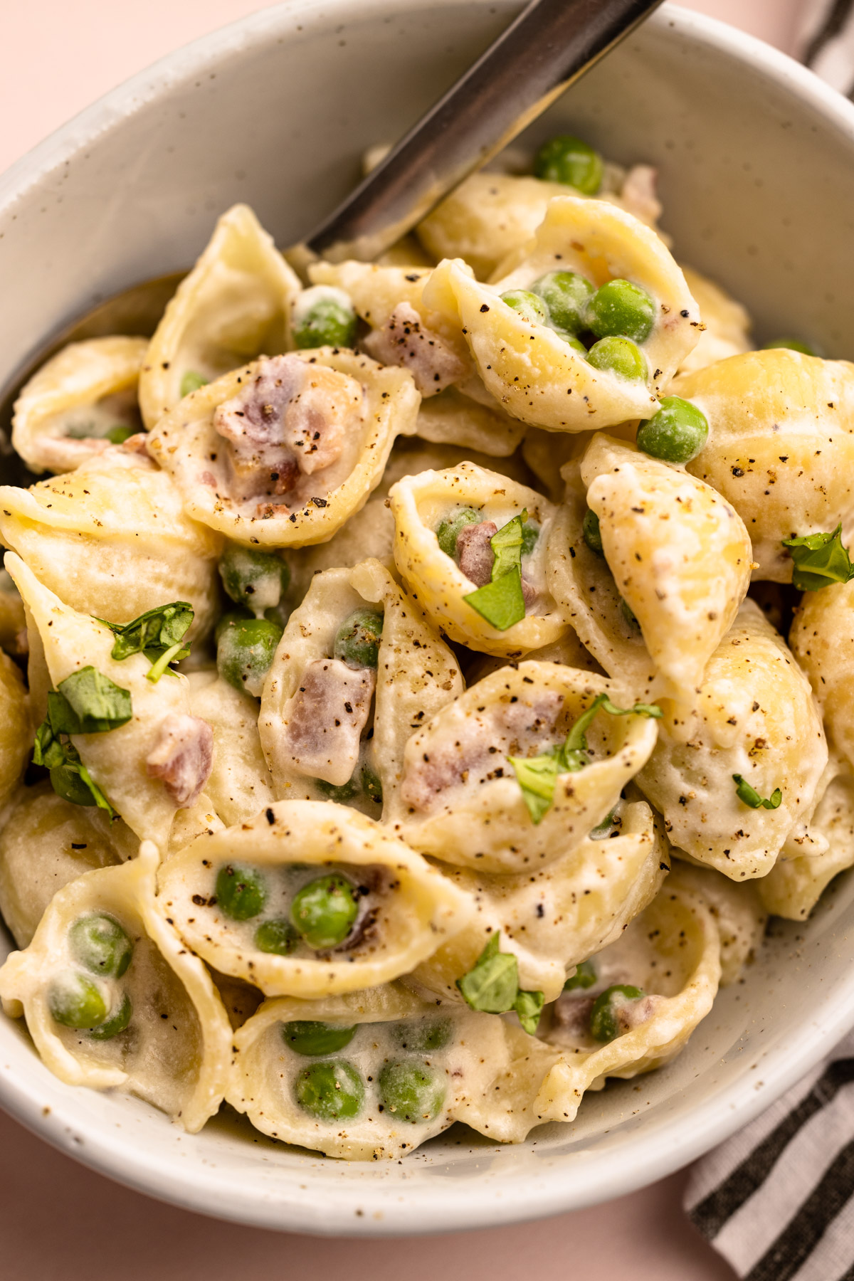 A bowl of pasta with peas and pancetta.