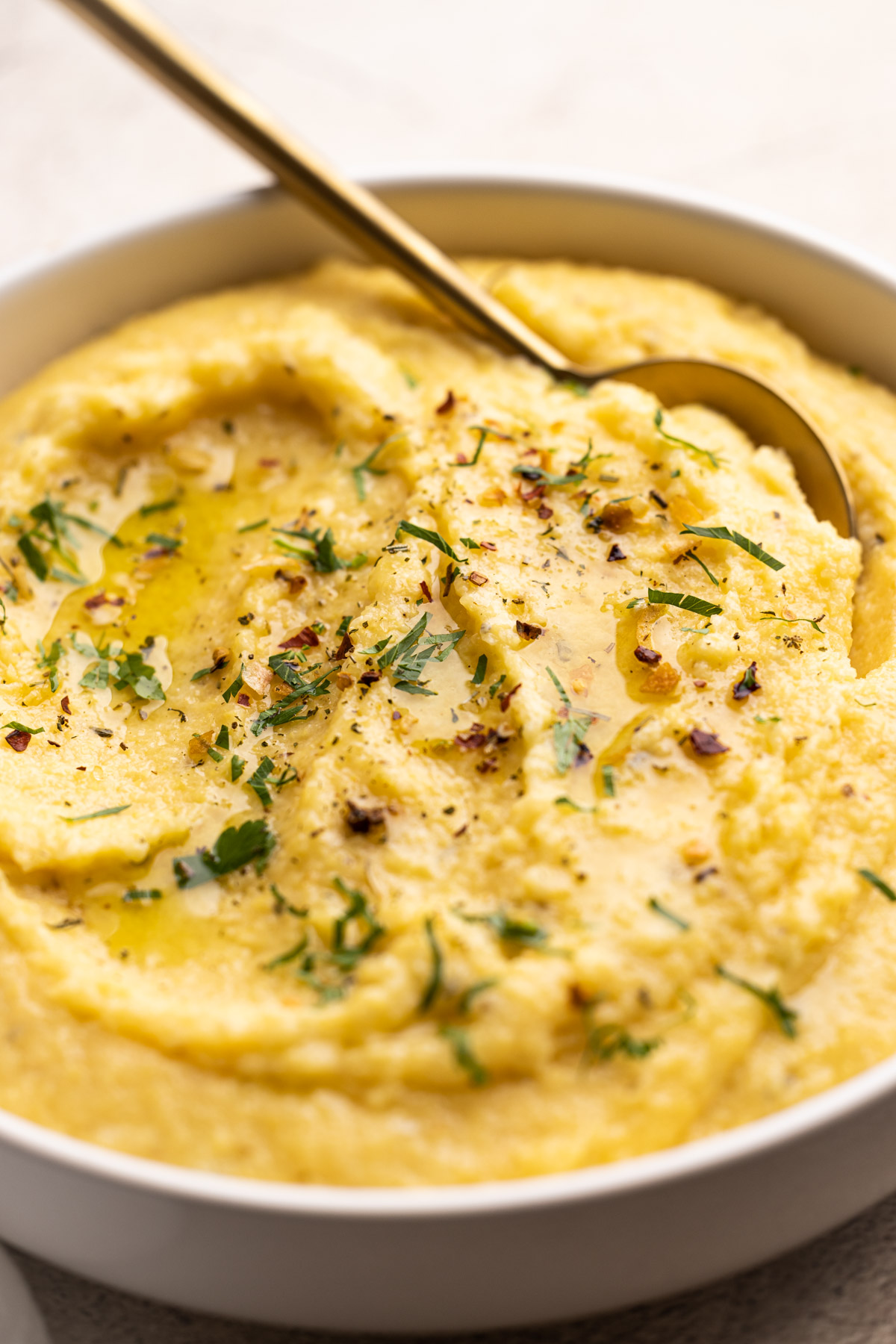 A bowl of creamy polenta with herbs and spices on top.