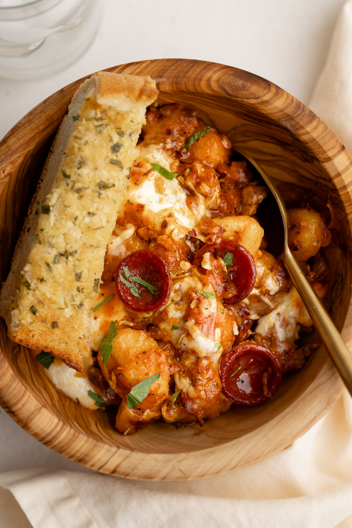 A bowl of skillet pizza gnocchi with a slice of garlic bread.