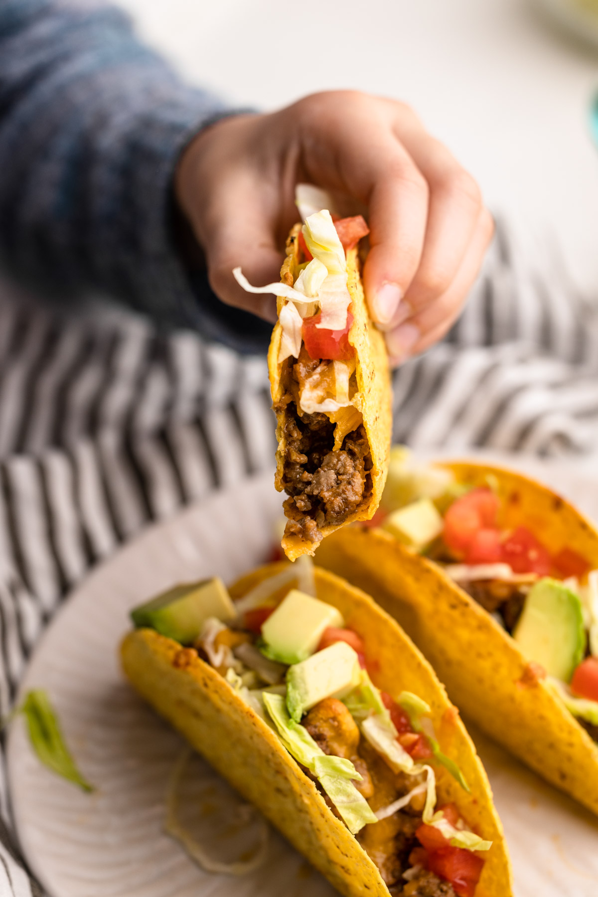 A small childs hand holding a beef taco baked in the oven.