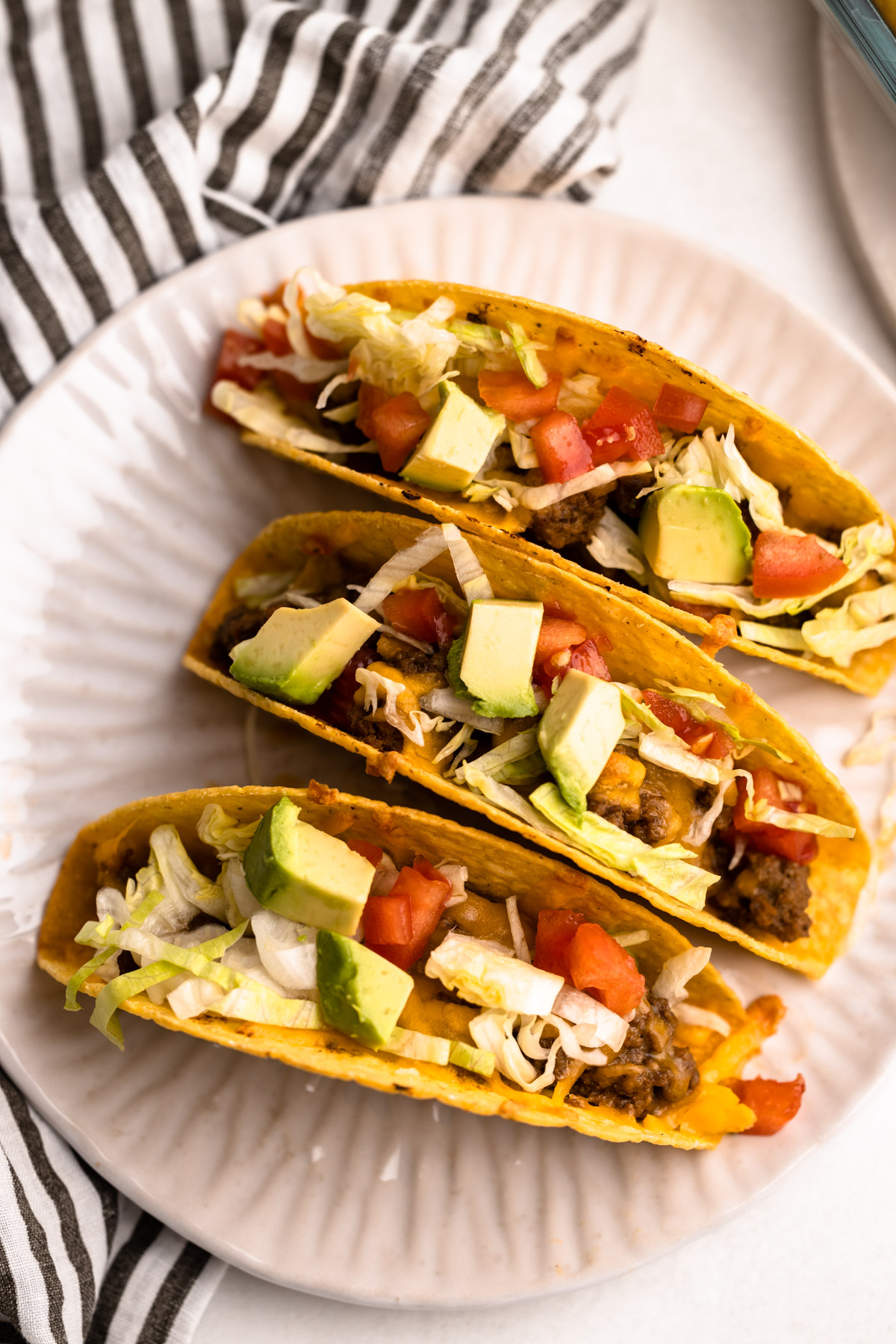 Three garnished oven tacos on a plate.