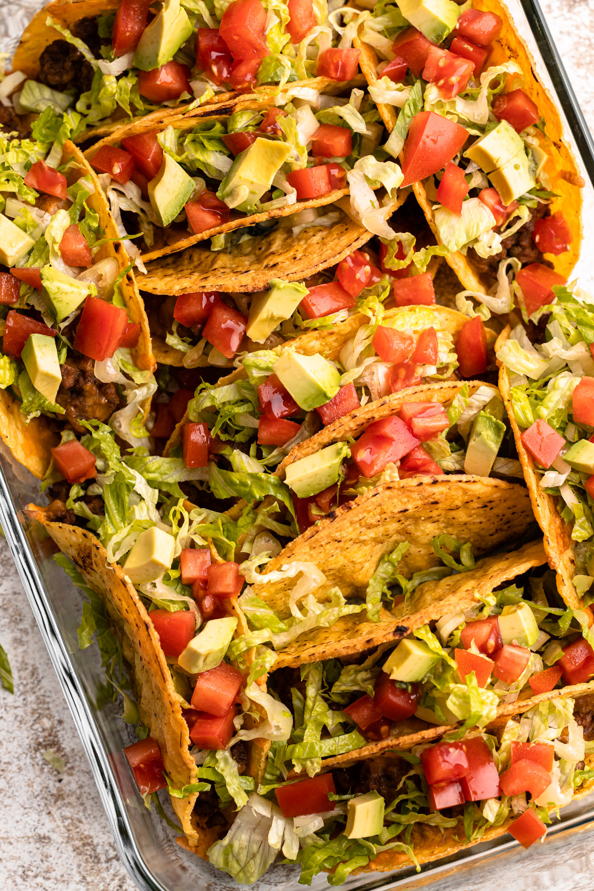 Oven tacos garnished with lettuce, tomato and avocado.