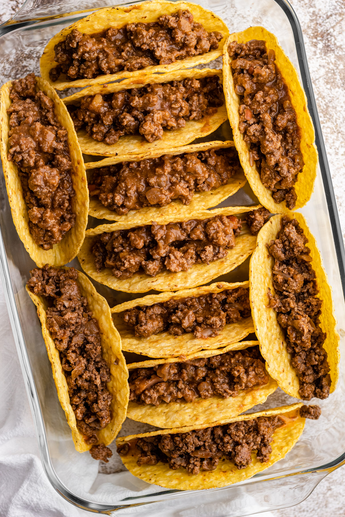 Crunchy taco shells with beef filling in a glass baking dish.