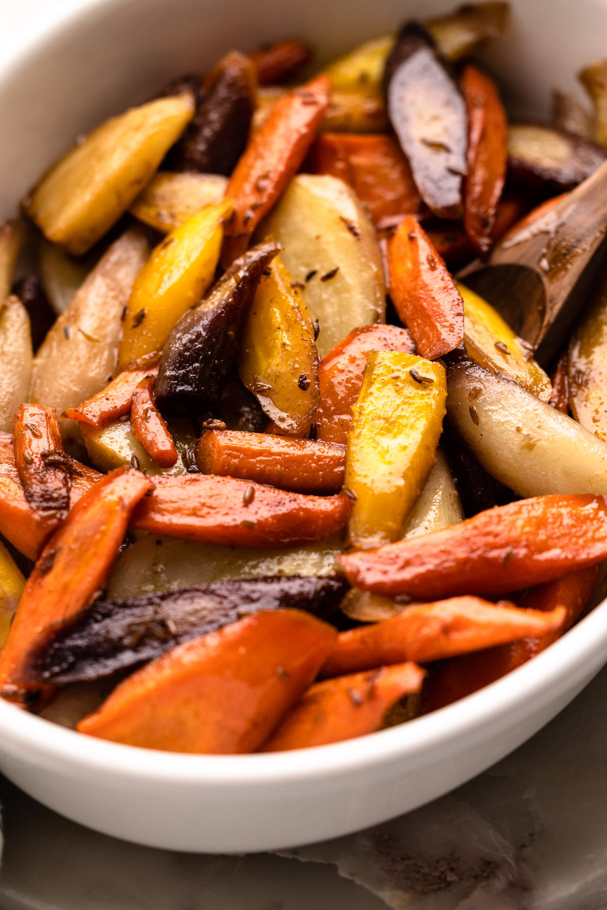 Honey roasted rainbow carrots with cumin in a serving container.