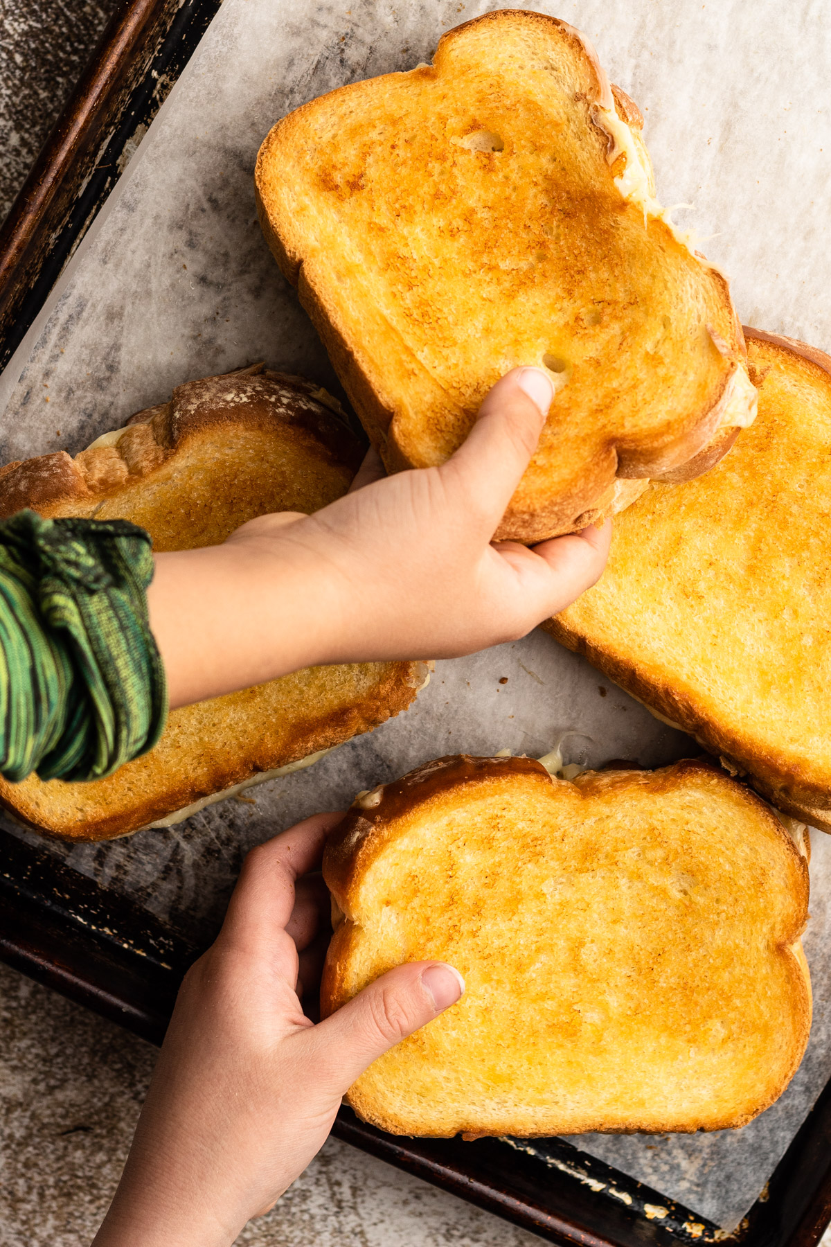 Kids grabbing grilled cheese from a (cooled down) sheet pan).