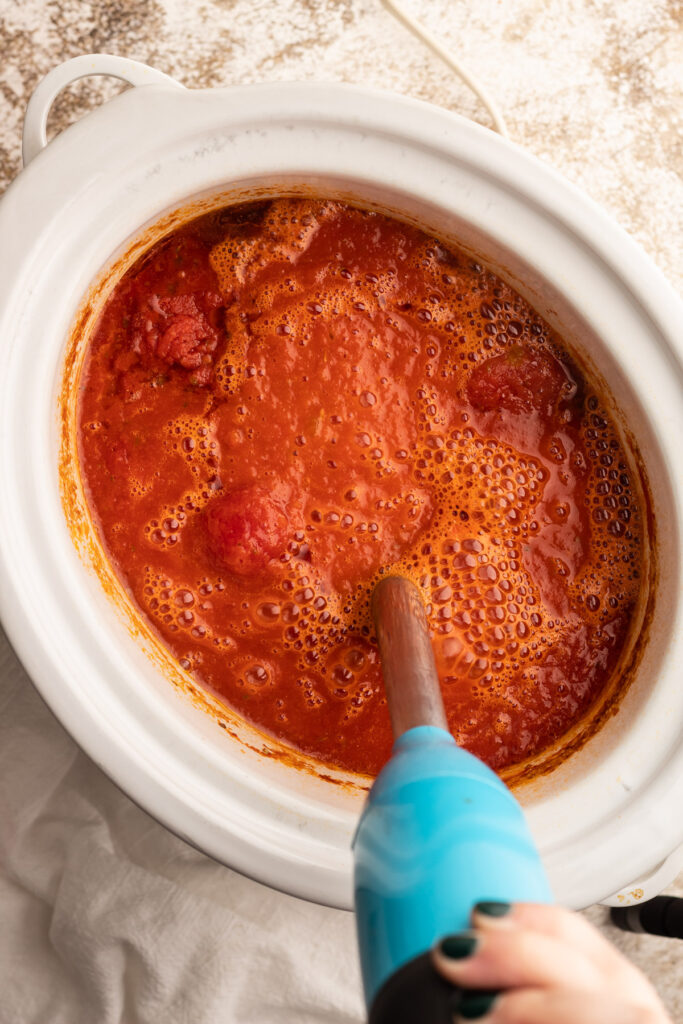 Tomato soup in a slow cooker being blended.