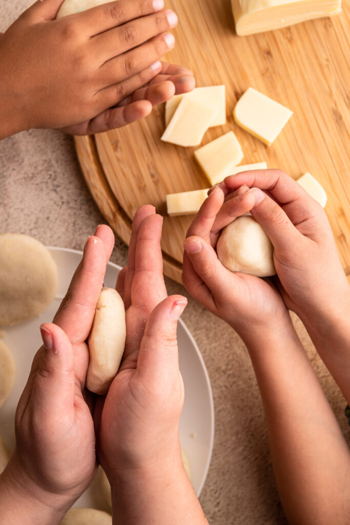 Three sets of family members hands making arepas.