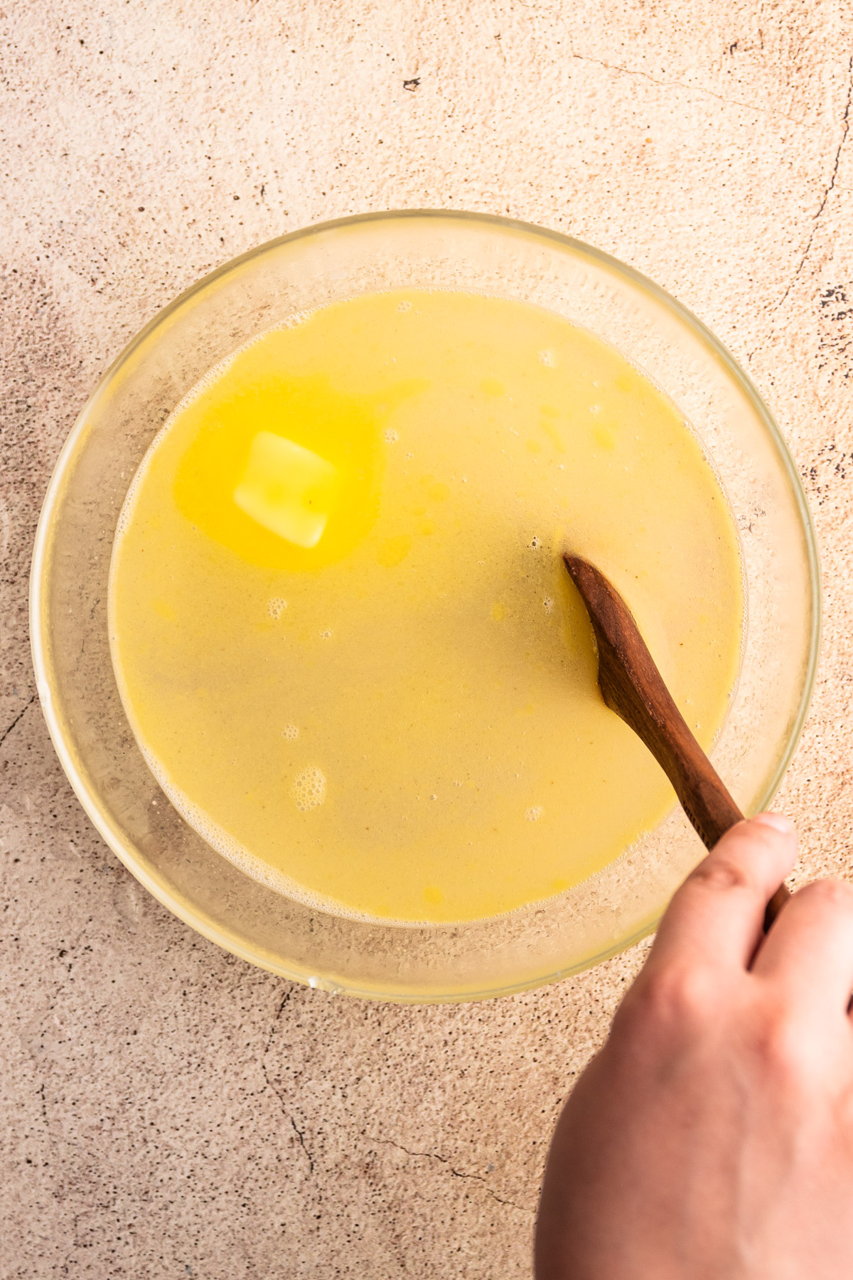 Making arepa dough by melting butter in warm water.