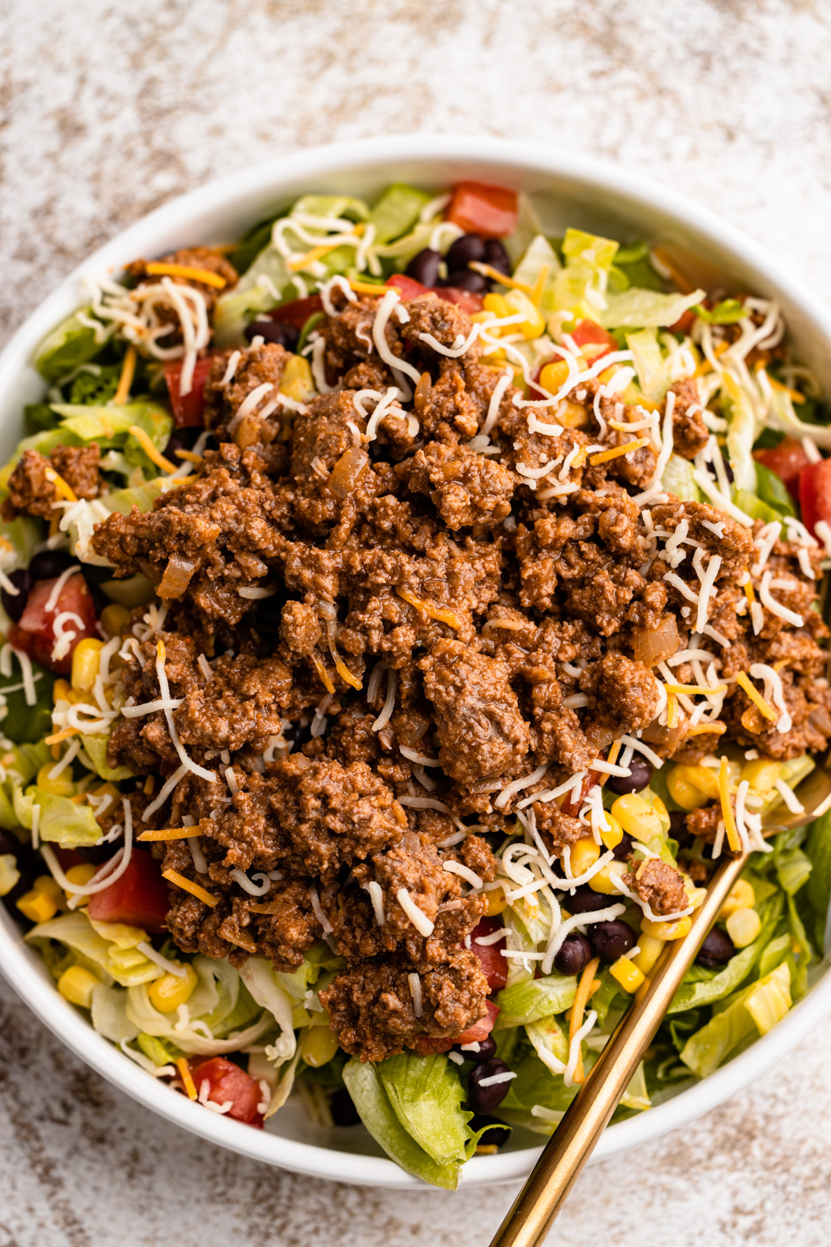 A salad with beef taco filling in top.