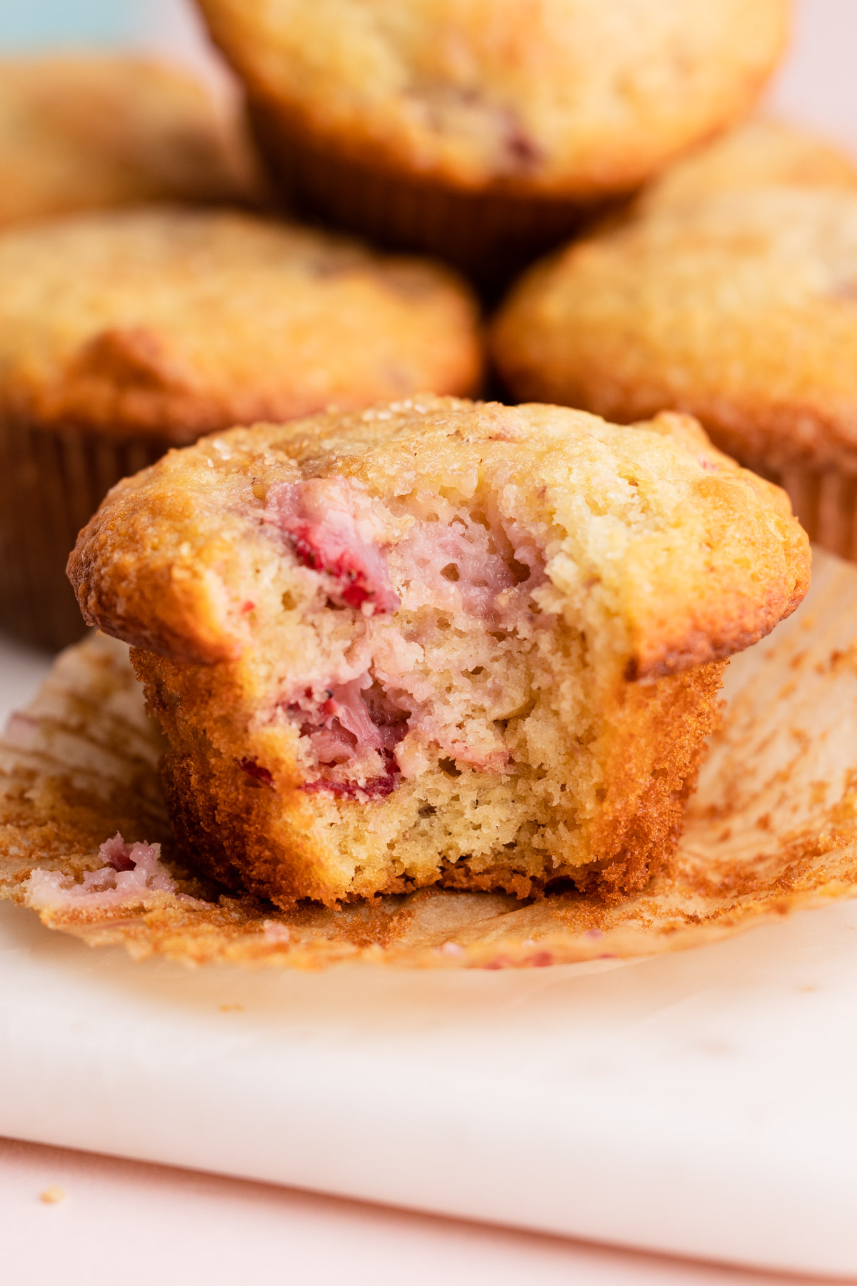 Buttermilk strawberry muffins with a bite taken from it to reveal their moist inside.