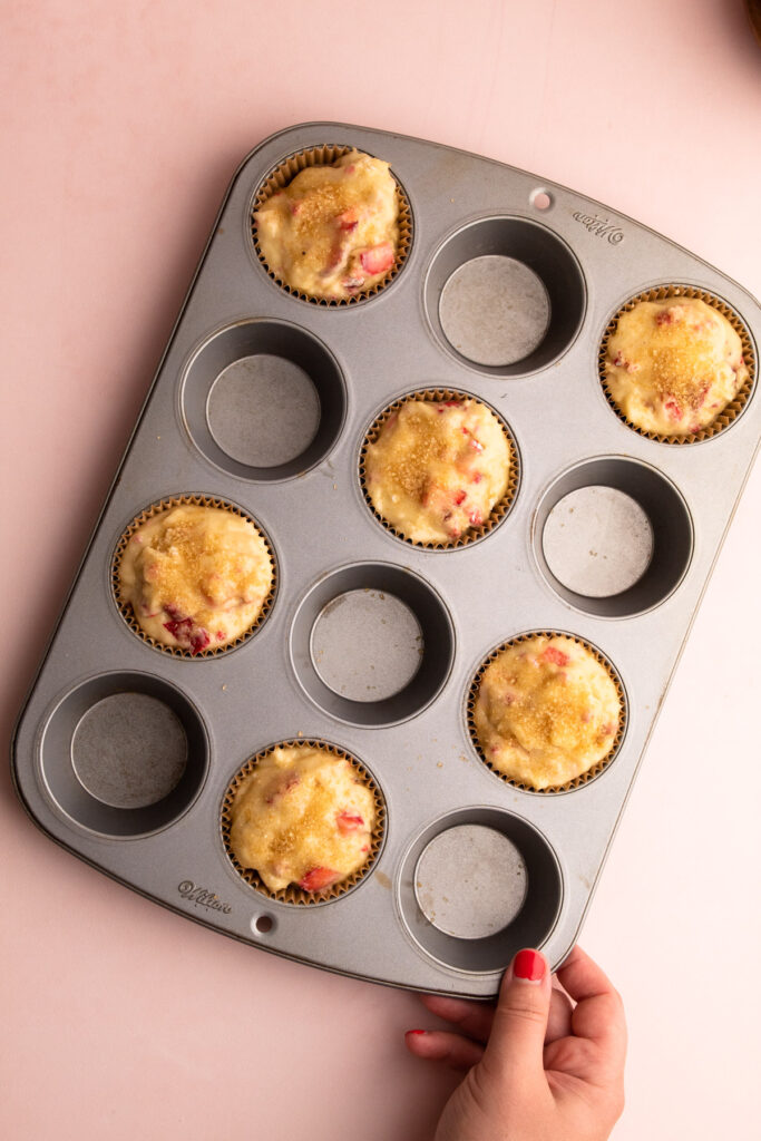 Strawberry muffin batter spaced out in a muffin tin.