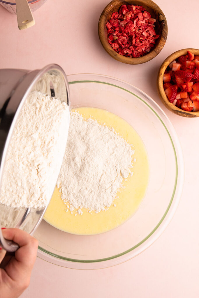 Pouring dry ingredients into wet to make strawberry muffins.