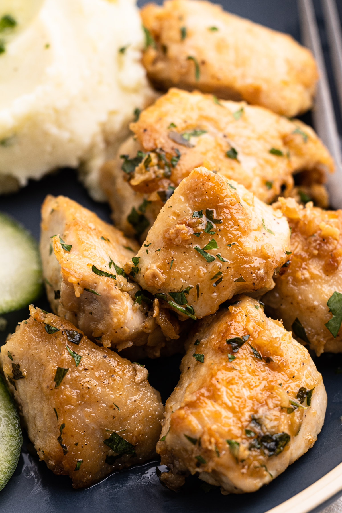 Garlic butter chicken bites on a plate with mashed potatoes.