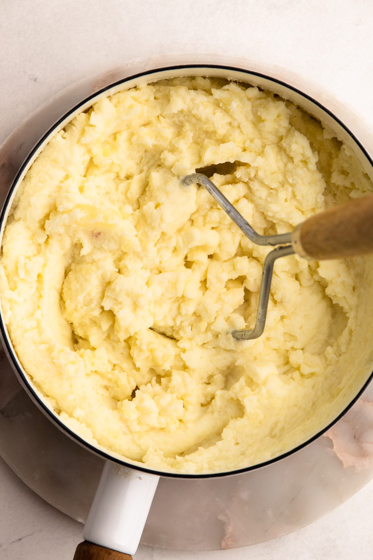 Mashing potatoes in a pot.