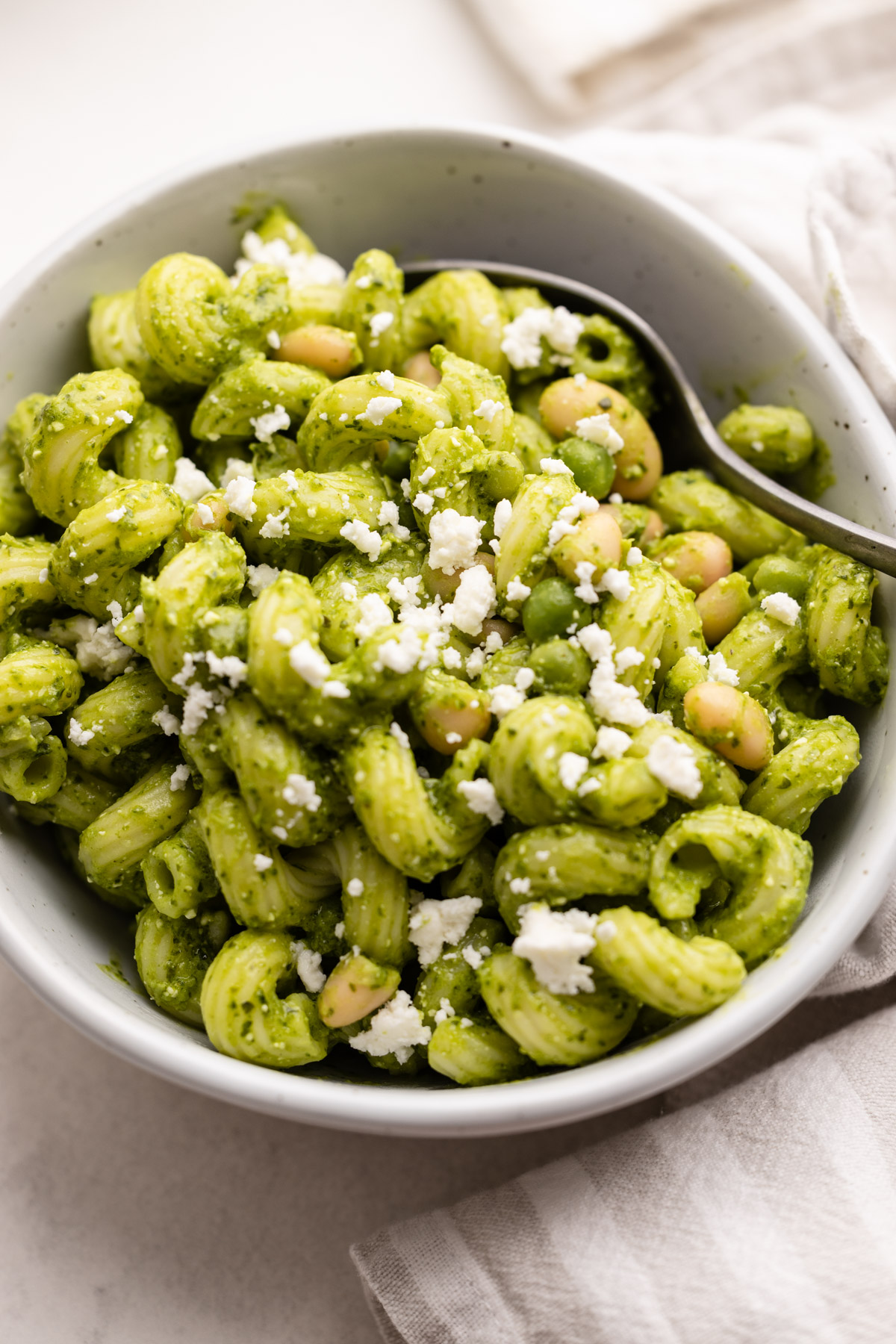 A bowl of kale pesto pasta with feta and lemon.