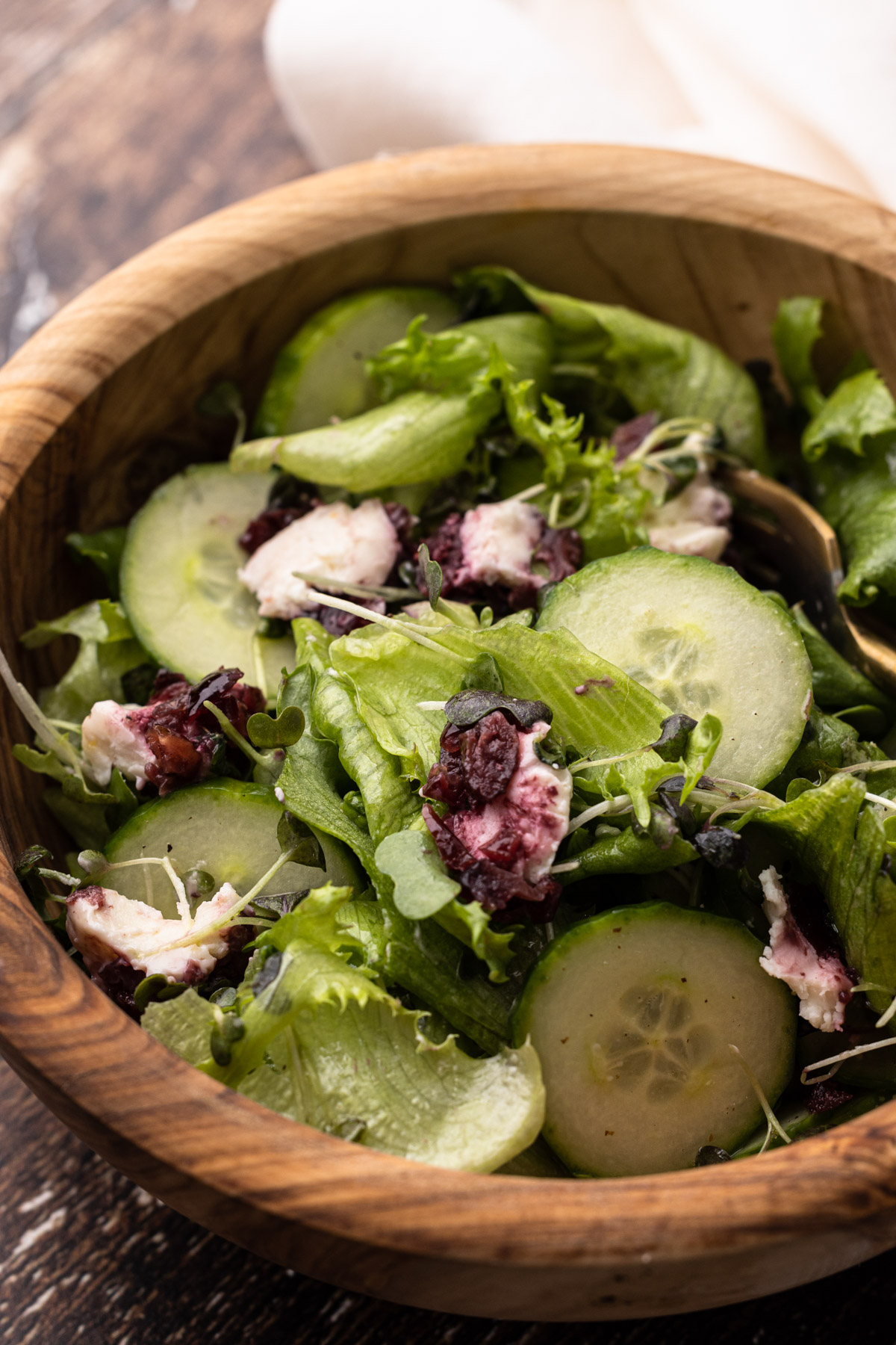 A bowl of goat cheese salad with cucumbers.