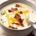 A bowl of potato cauliflower soup topped with bacon and cheddar.