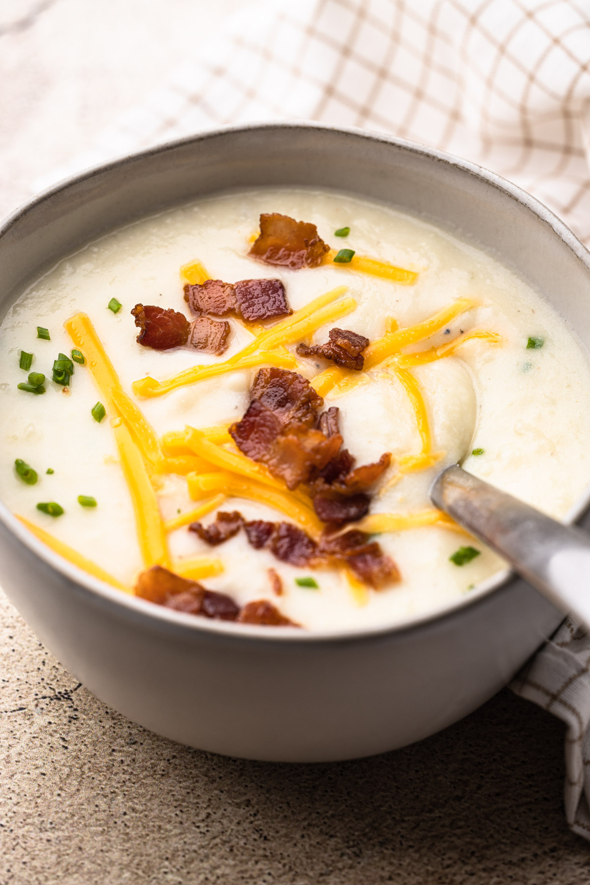 A bowl of potato cauliflower soup topped with bacon and cheddar.