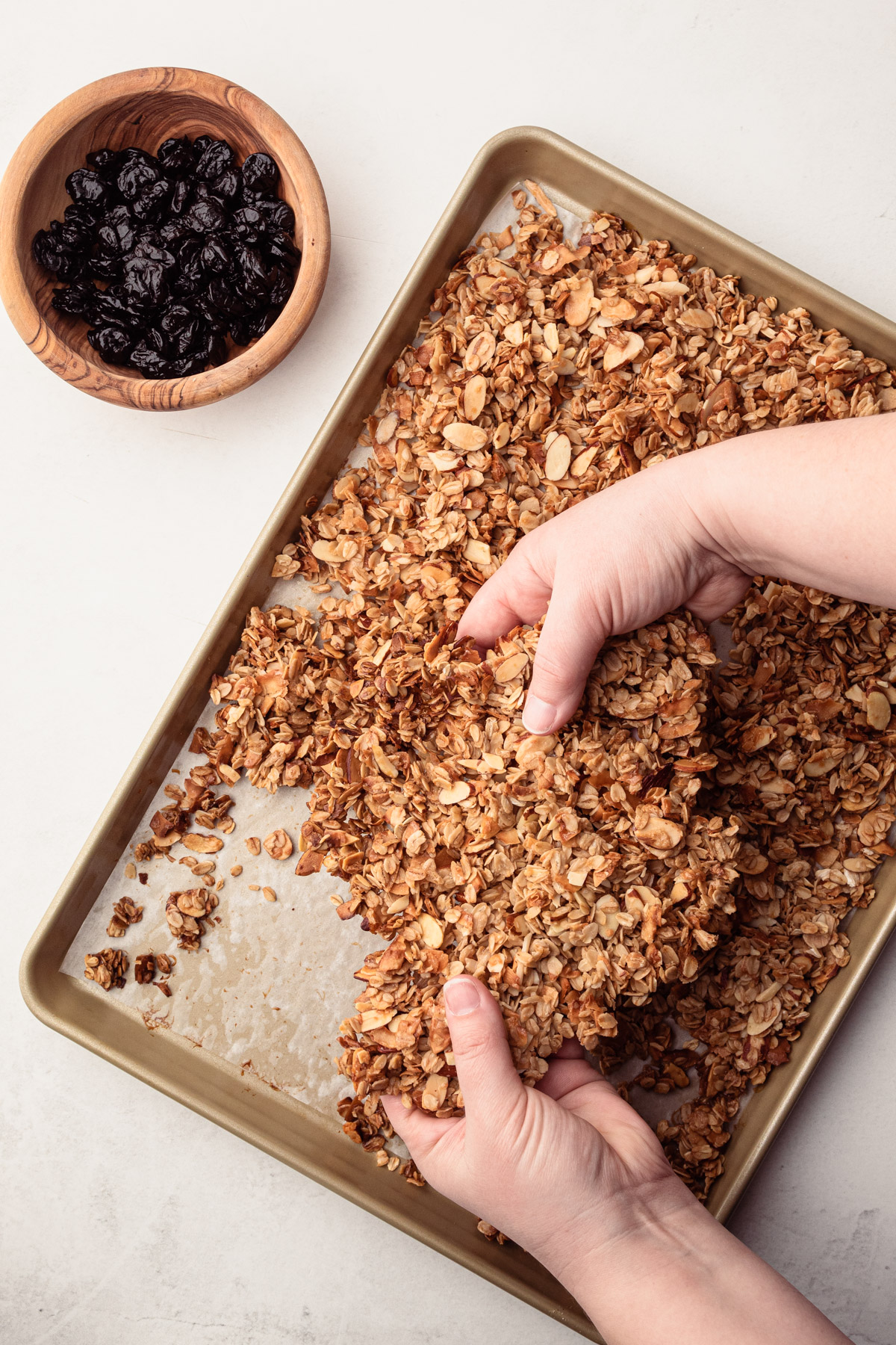 Breaking up baked almond cherry granola.