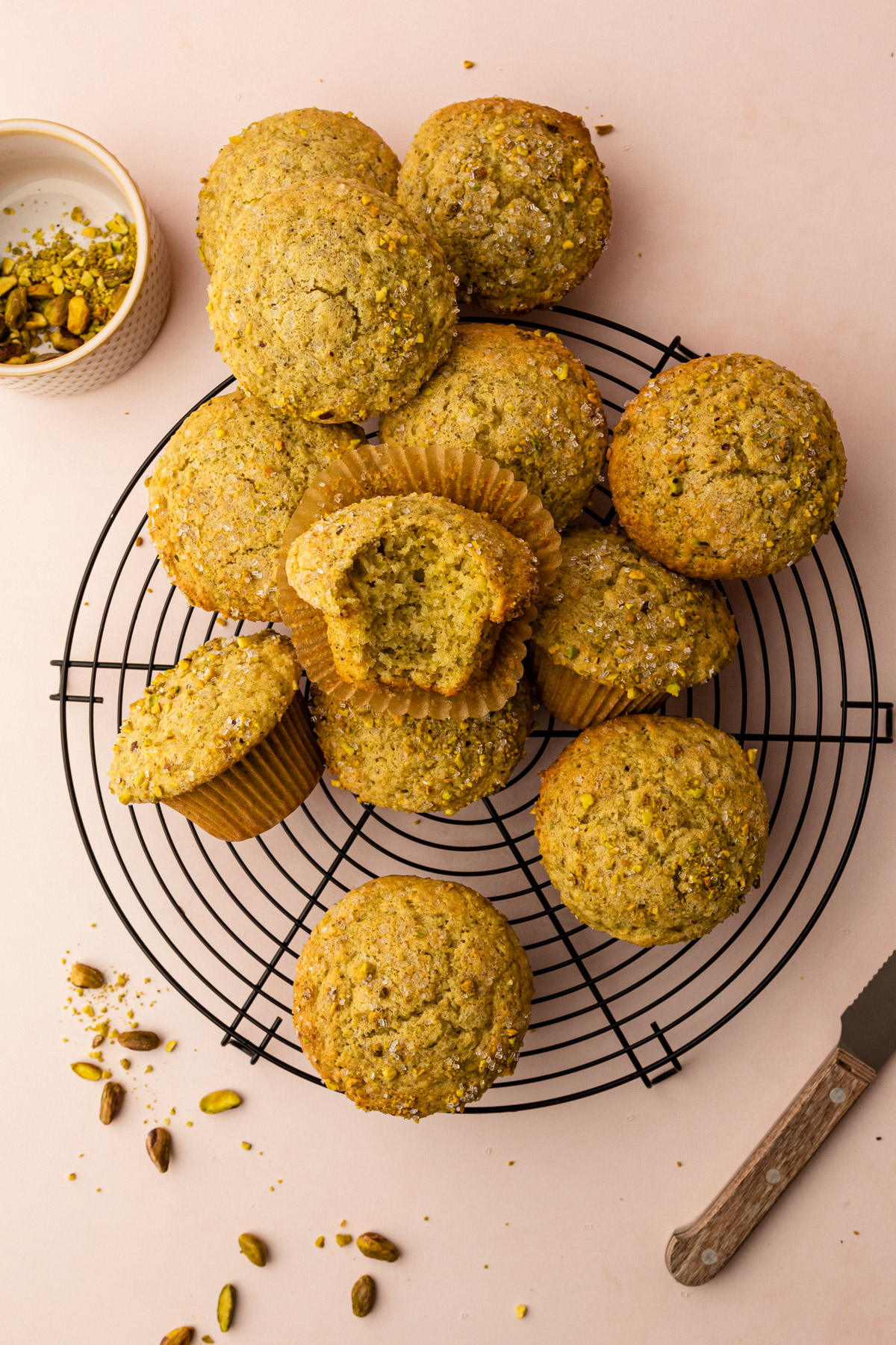 Many pistachio muffins on a cooling rack.