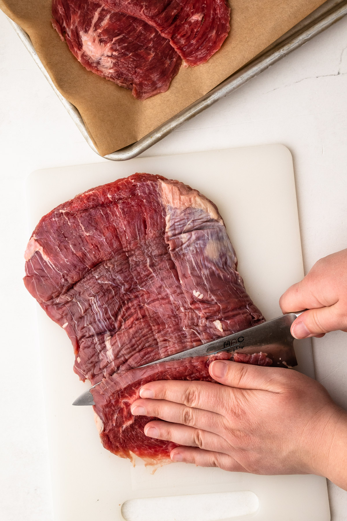 Slicing flank steak for carne bistec.