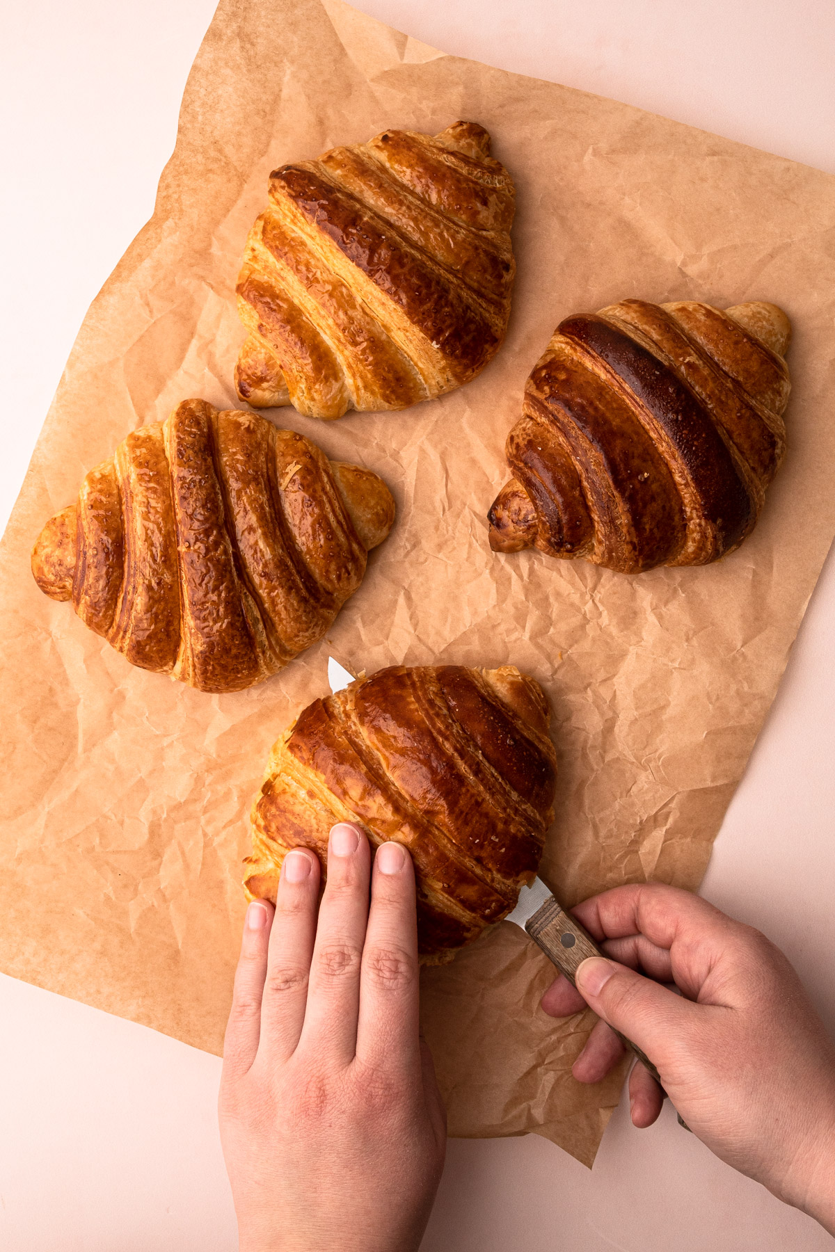 Croissants being sliced in half for croissant French toast.