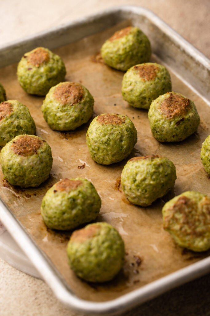 Pesto chicken meatballs on a baking sheet.