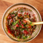 A mason jar with a spoon in it filled with Colombian-style Aji.