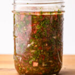 A mason jar of prepared aji on a cutting board.