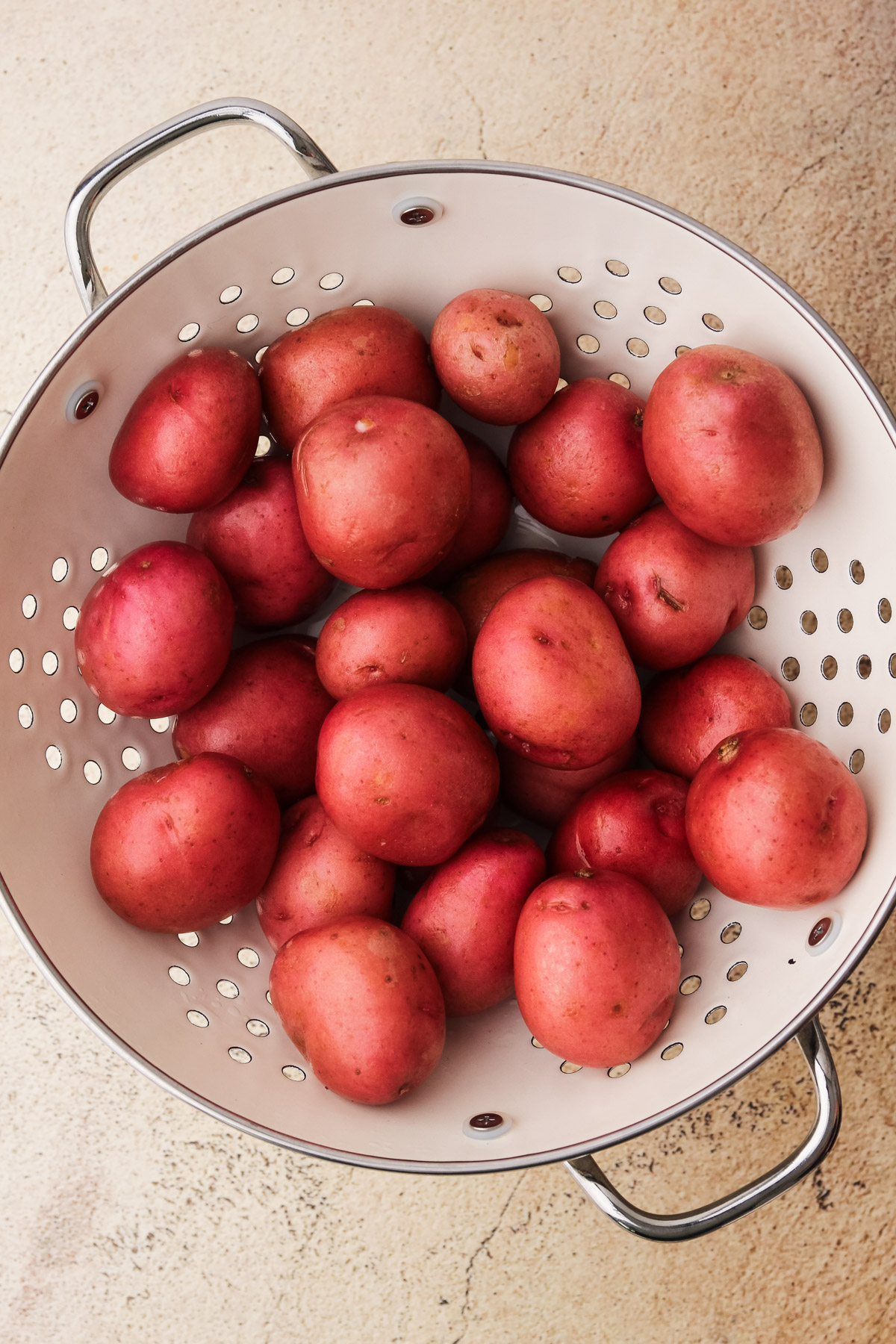 Red potatoes in white colander.