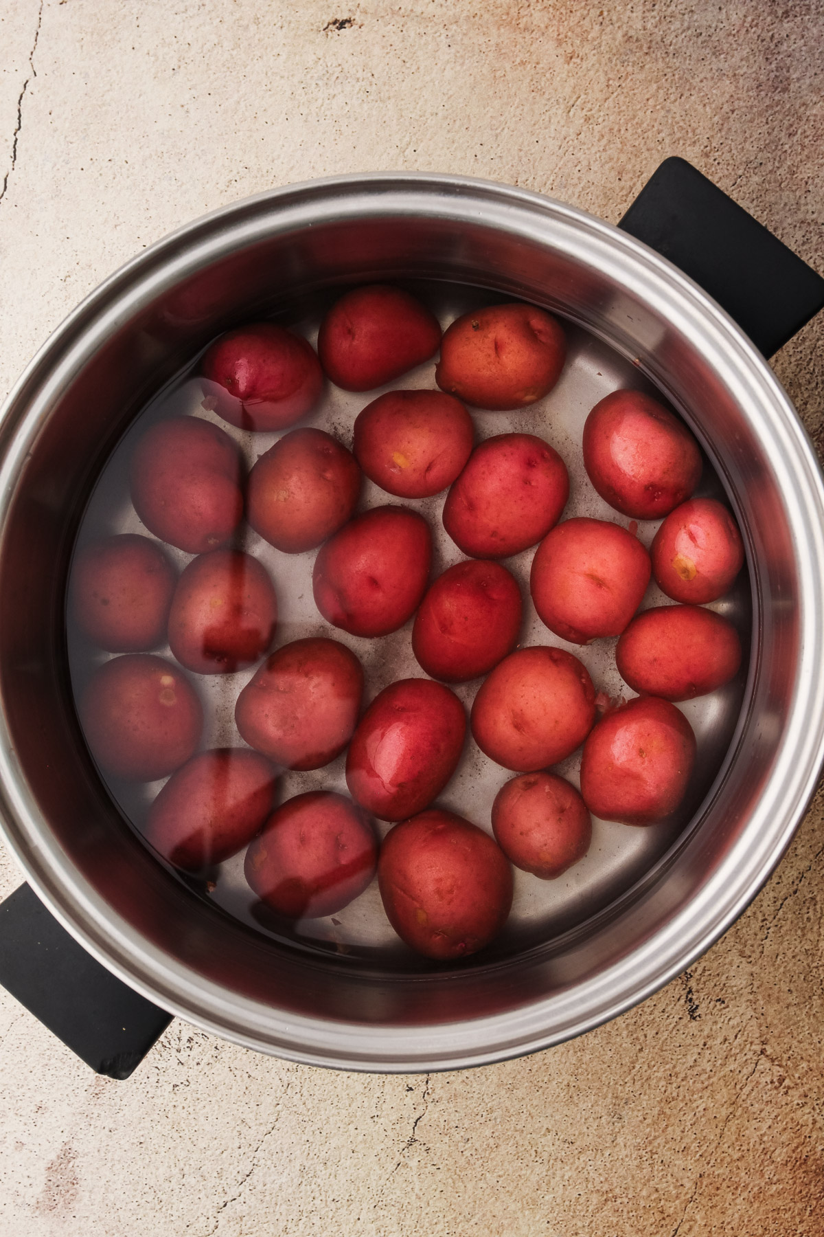 Red potatoes in water in a pot.