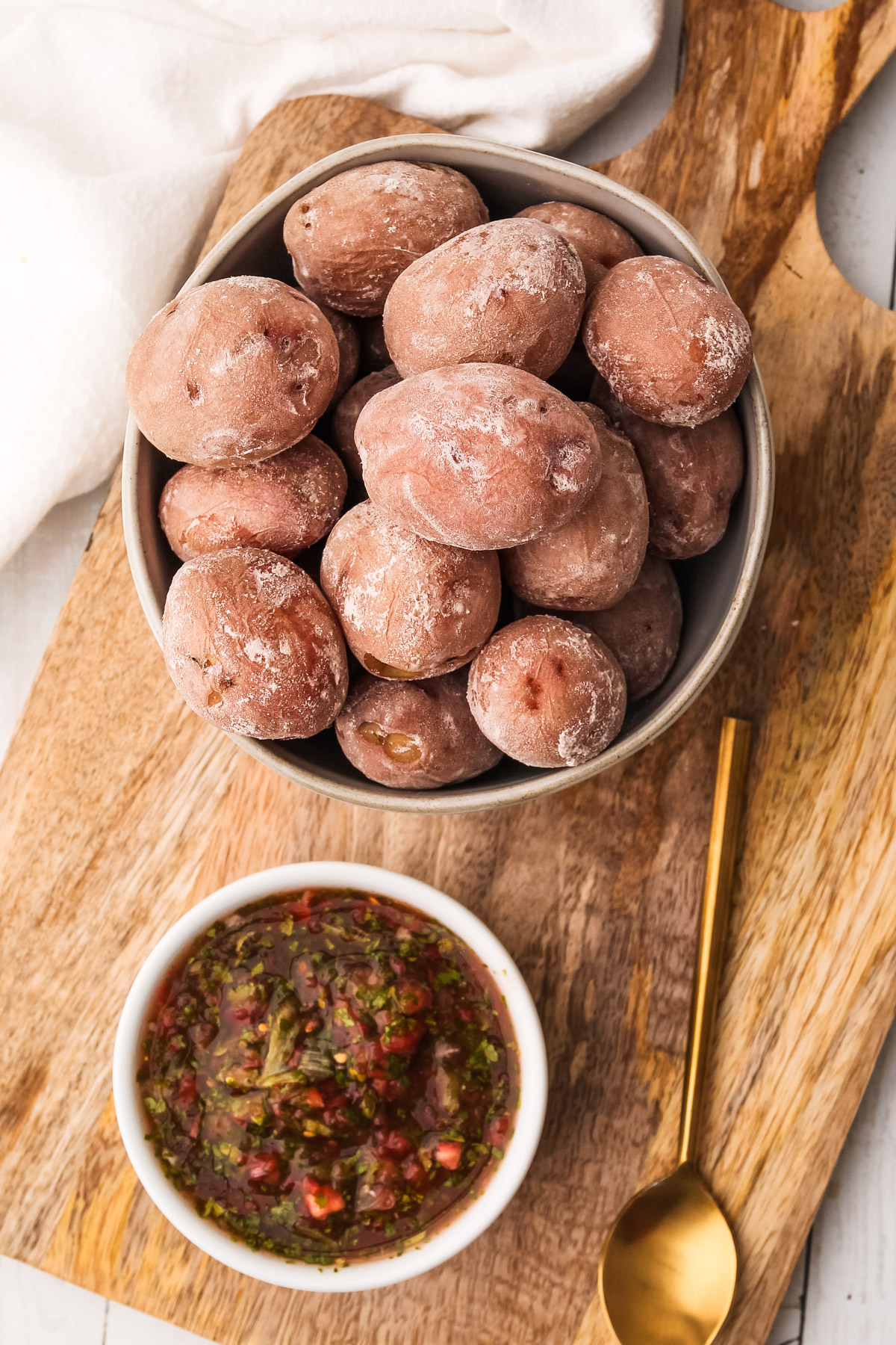 A bowl of salted potatoes on a cutting board with salsa for serving.