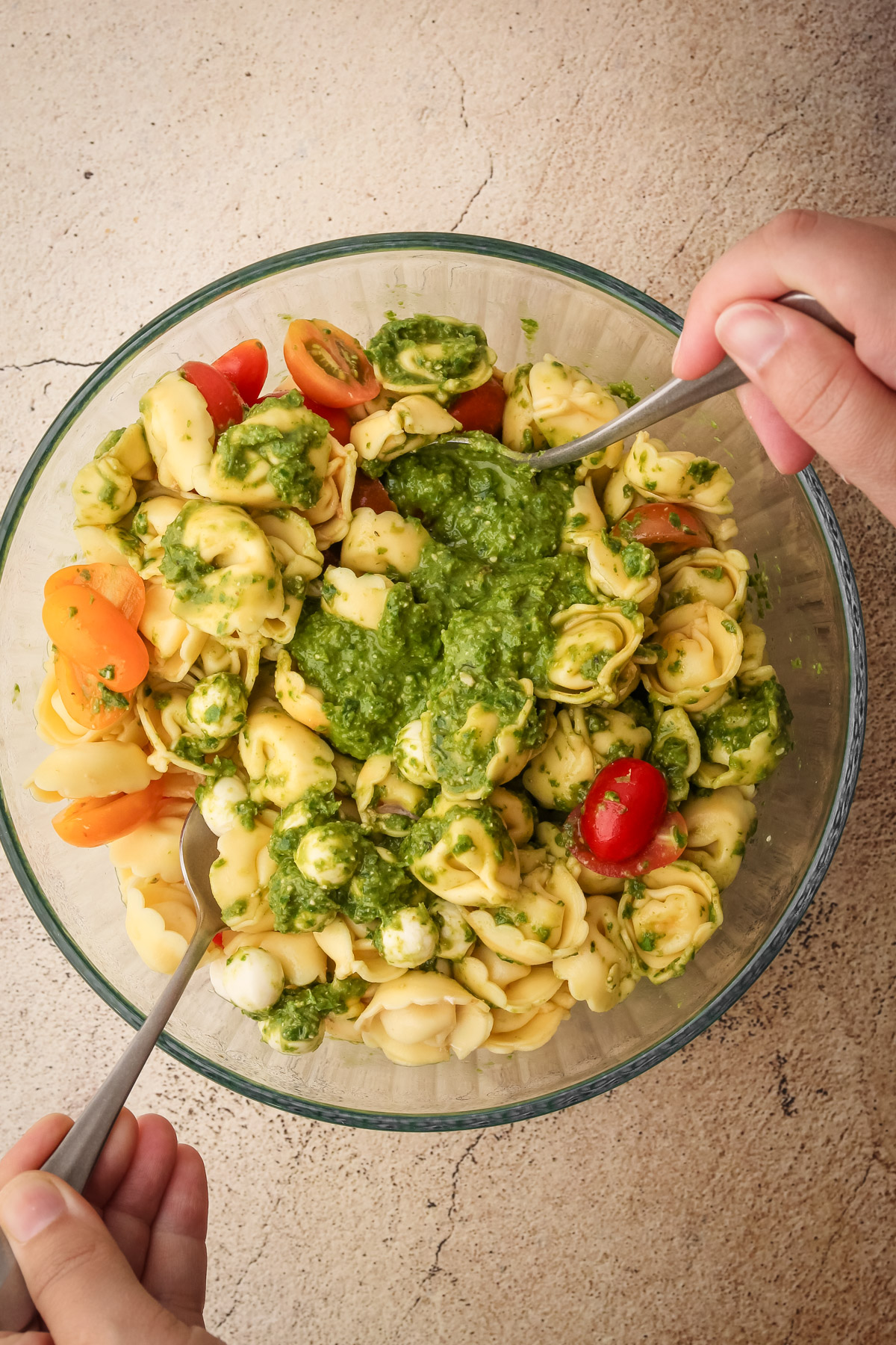 Tossing together the tortollini salad with two spoons.