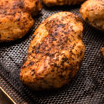 Four cooked air fryer chicken breasts on an air fryer rack.
