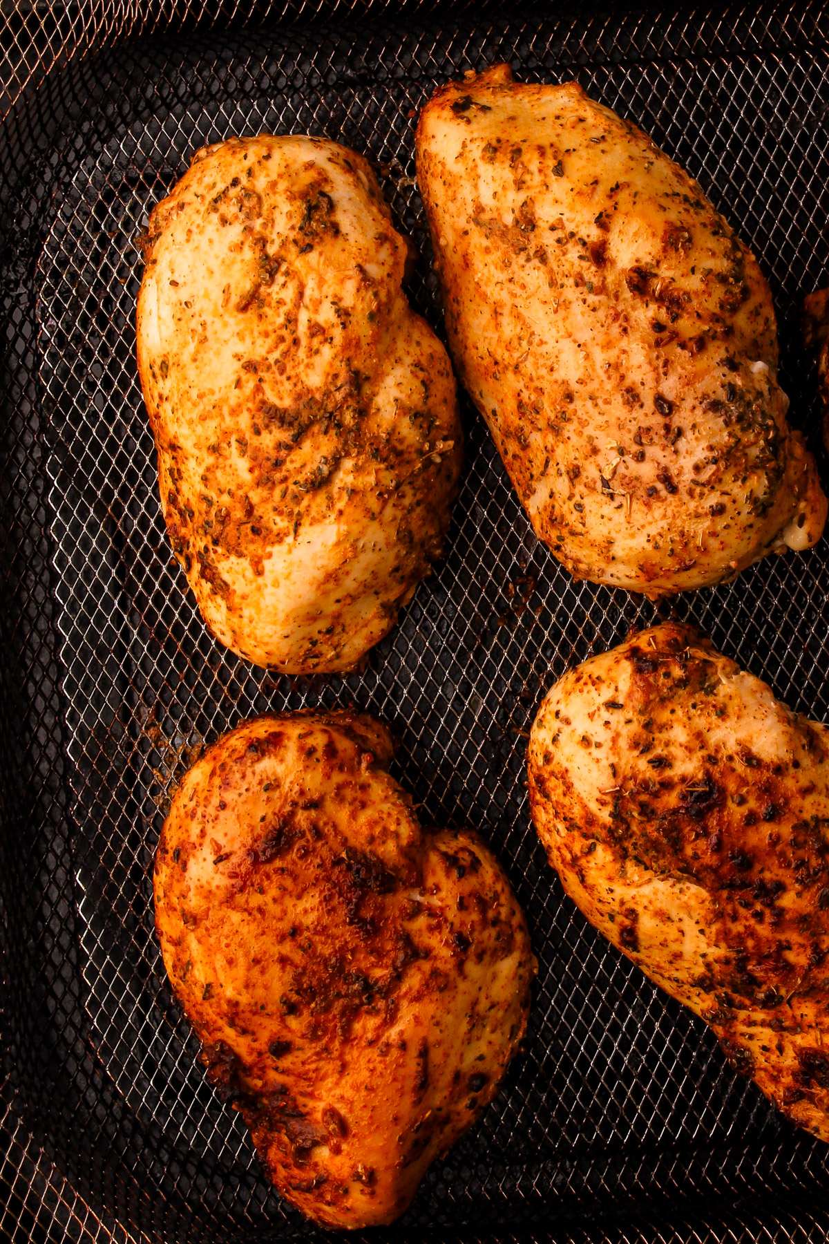 PerfeChicken breasts on the air fryer tray uncooked but with spices.