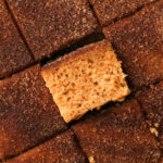 Square slices of baked apple cider donut cake, with one slice turned on its side to see the fluffy interior