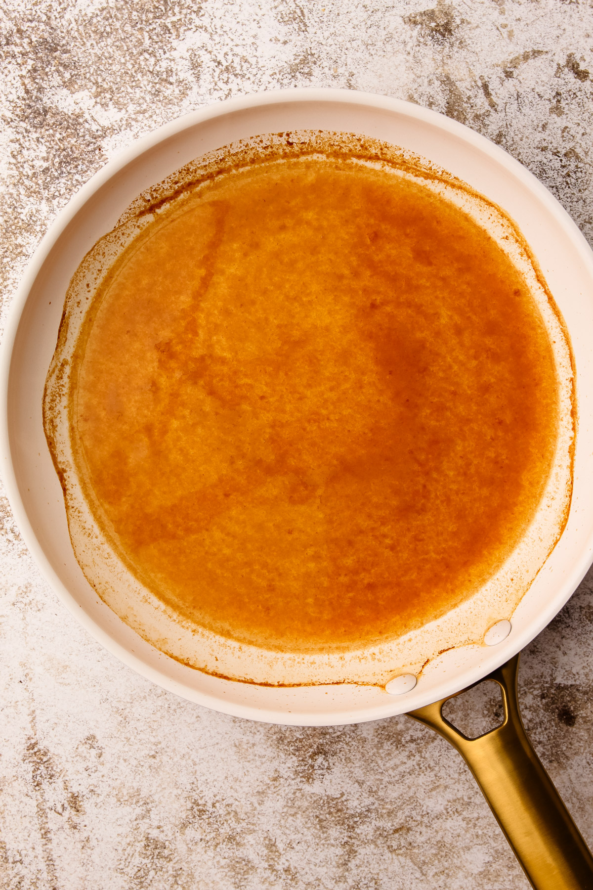 Reduced apple cider in a skillet, with browned edges around the circumference