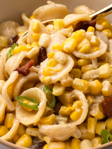 A close up of the creamy corn pasta with bacon in a bowl.