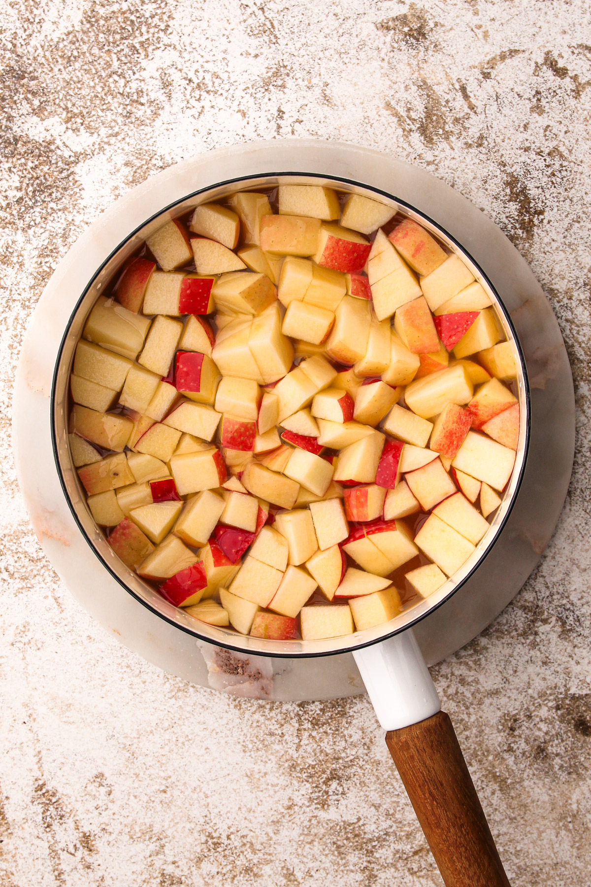 Cider and diced apples in a white pot.