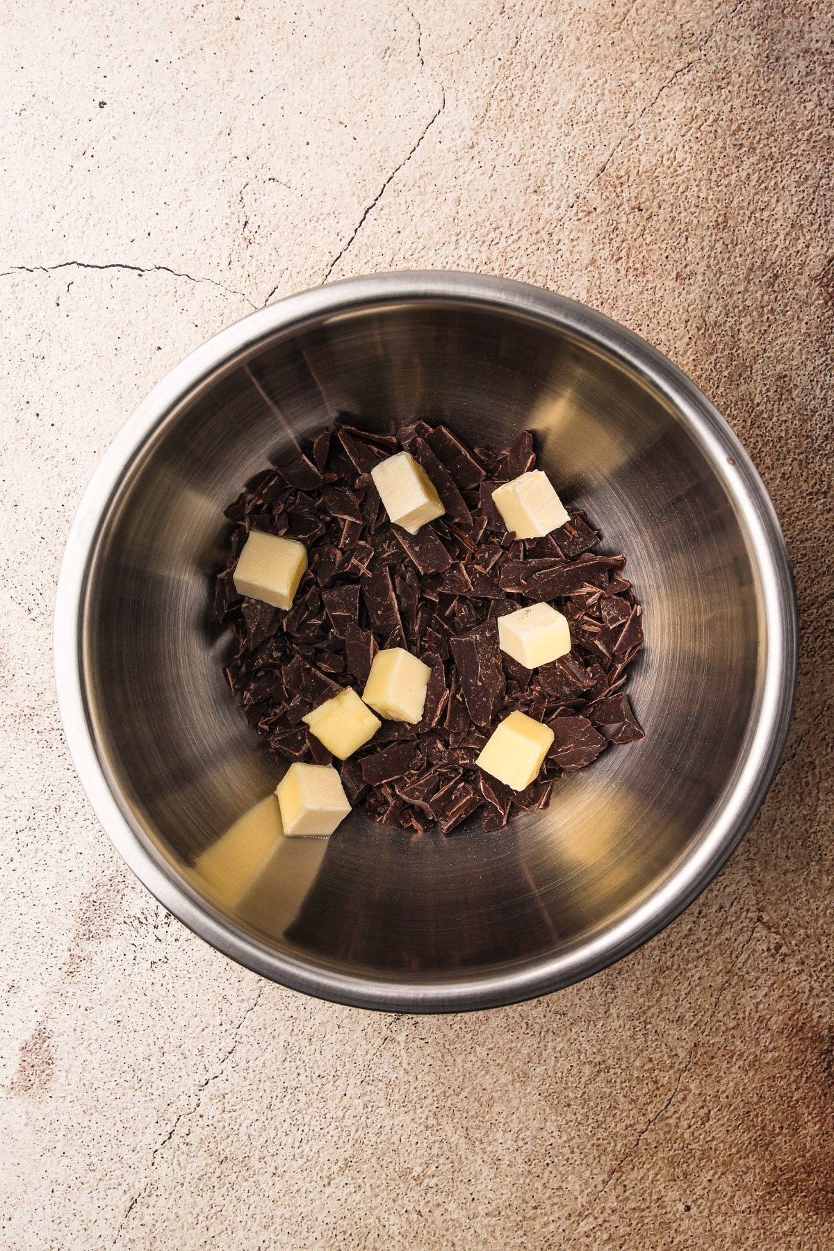 Chopped chocolate and cubes of butter combined in a bowl for Dirt Pudding Cups.