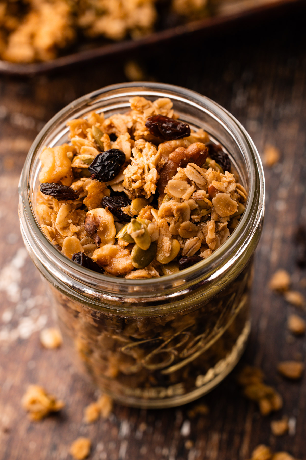 A glass jar filled with baked maple walnut granola.