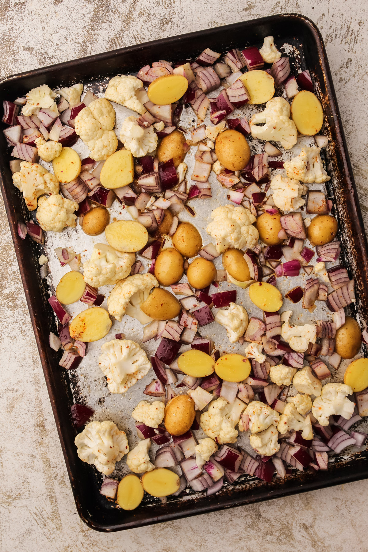 Raw vegetables for sheetpan kielbasa on a baking sheet.