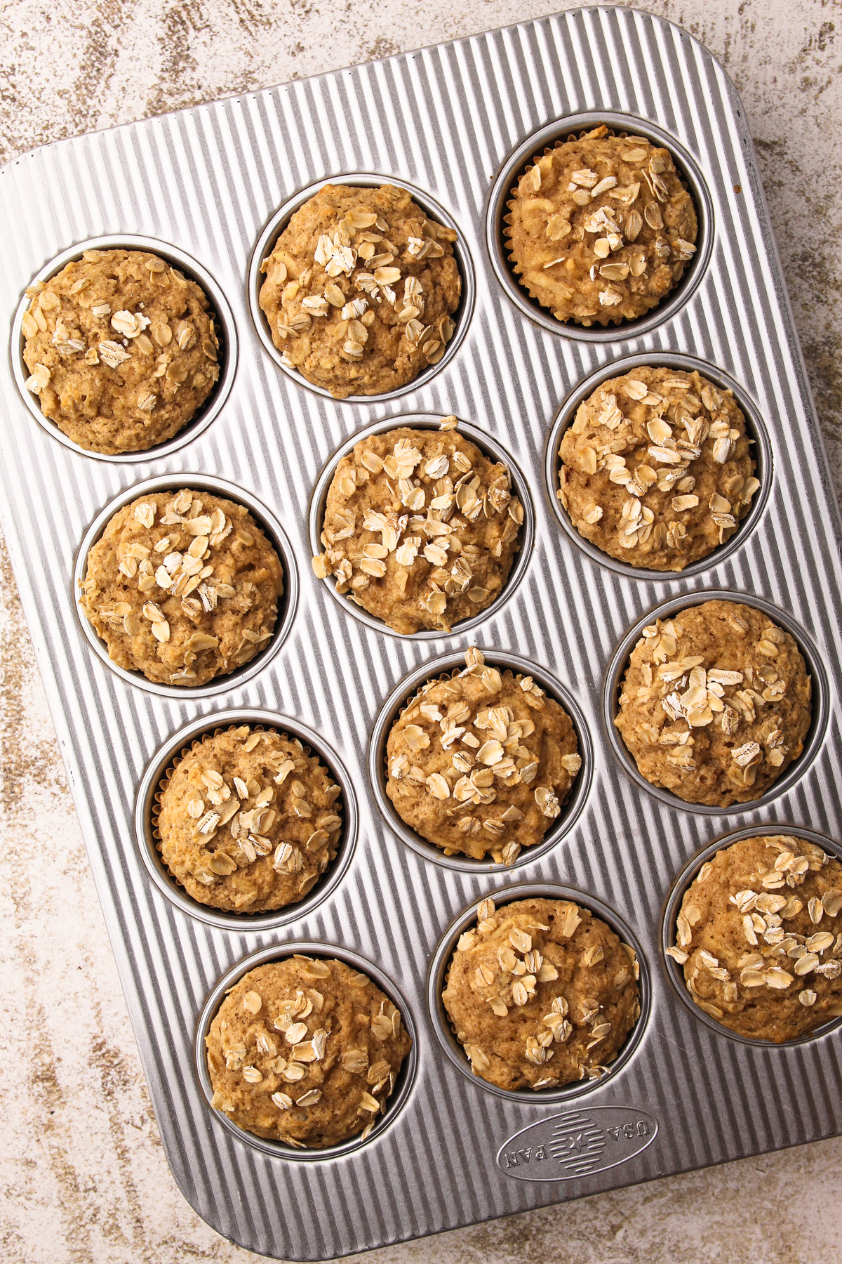 Baked healthy apple oat muffins in a metal muffin tin.