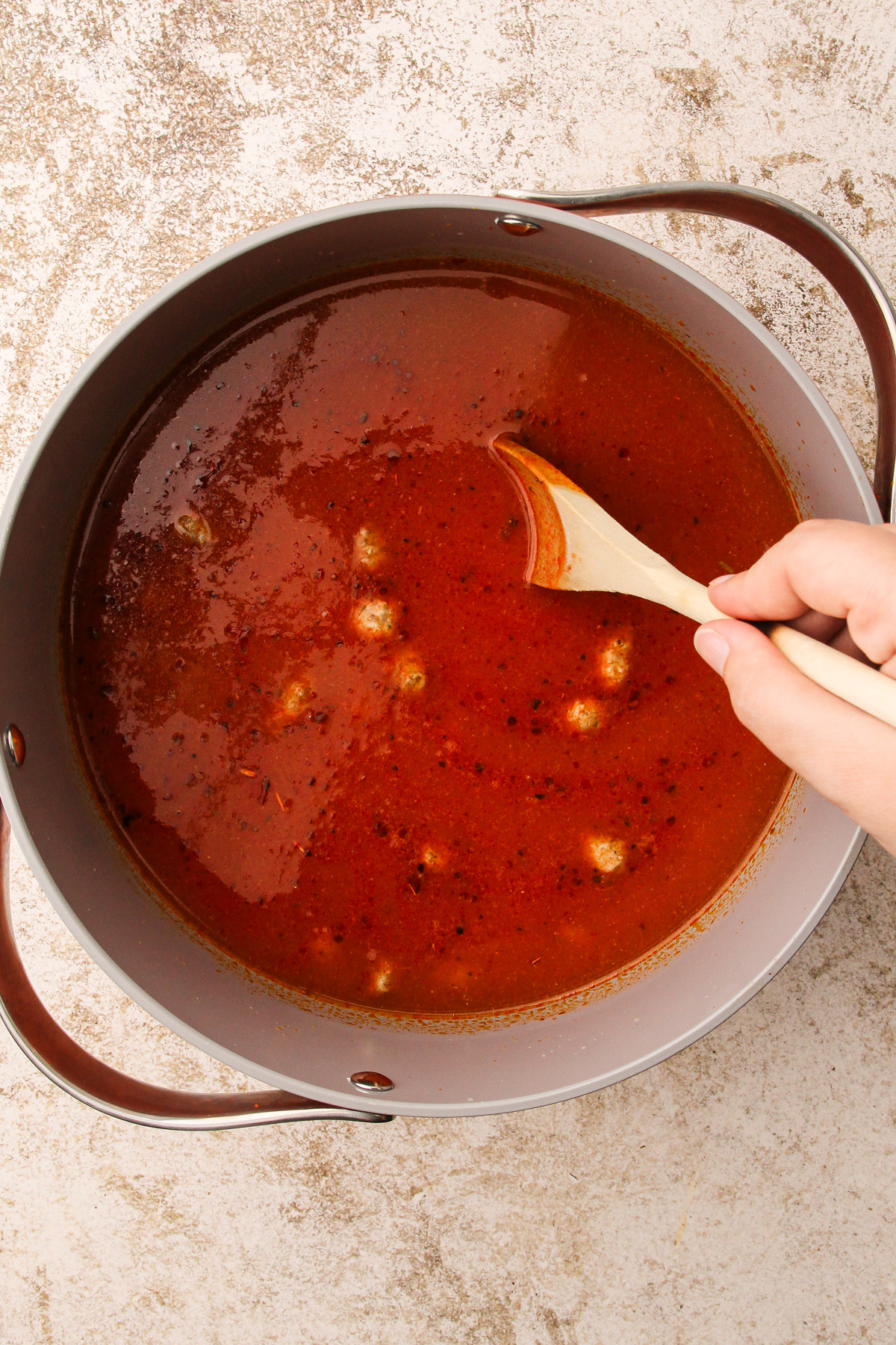 A broth tomato sauce with meatballs in a pot.