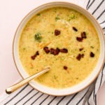 A bowl of Broccoli Cheddar Bacon Soup with a spoon in it.