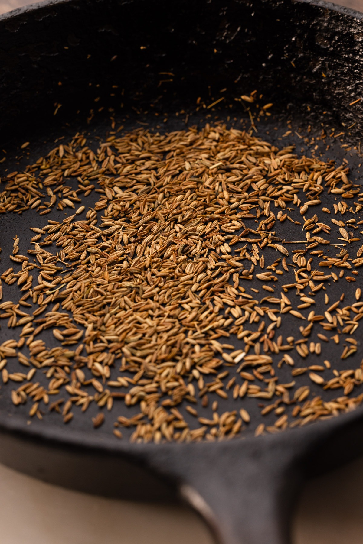 A skillet of toasted cumin seeds for winter slaw.